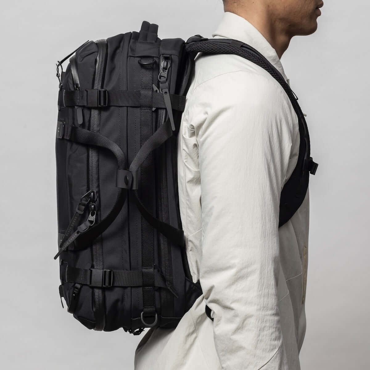 Black Ember FORGE 40L backpack displayed side view, showcasing its expandable design and versatile carry options.