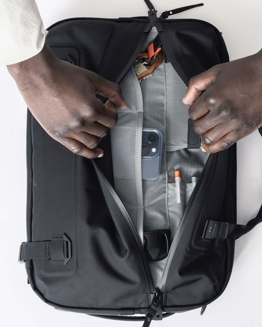 Black Ember FORGE SB 20L Minimalist Soft Brief open to reveal organized compartments holding phone, keys, pens, and sunglasses. Ideal EDC briefcase.