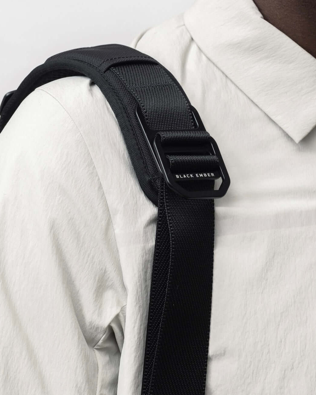 Close-up of Black Ember FORGE SB 20L Minimalist Soft Brief shoulder strap worn over a white shirt, showcasing durable hardware and sleek design.