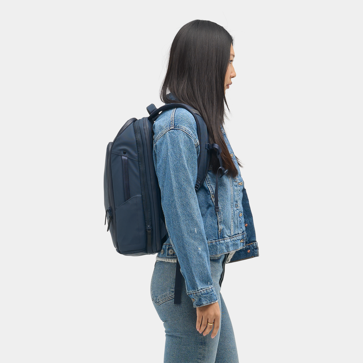 Nomatic Travel Pack in navy blue worn by woman, showcasing slim profile and ergonomic fit for everyday or travel use.