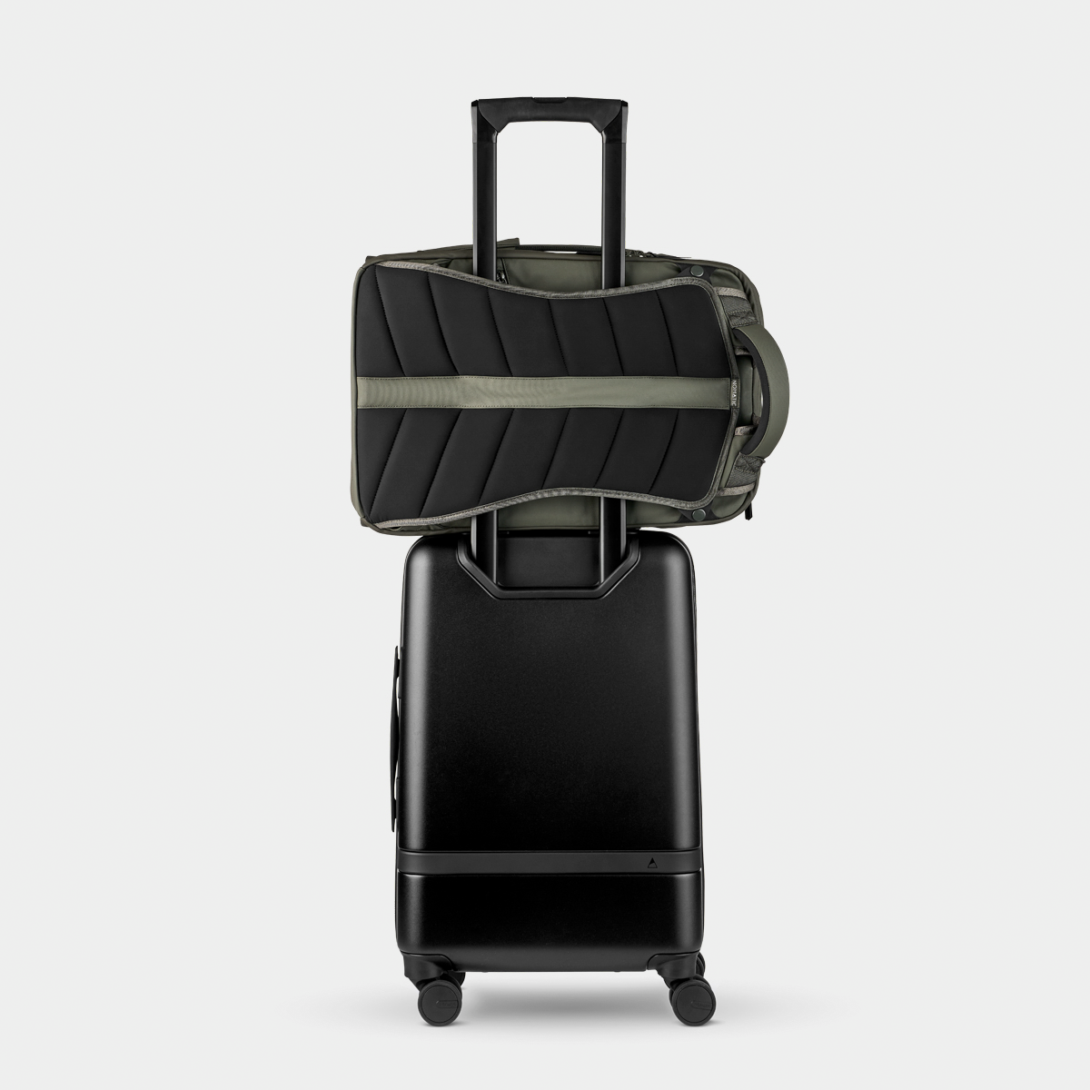 Nomatic Travel Pack in olive green securely attached to a black rolling suitcase handle, showcasing travel-ready design and luggage compatibility.