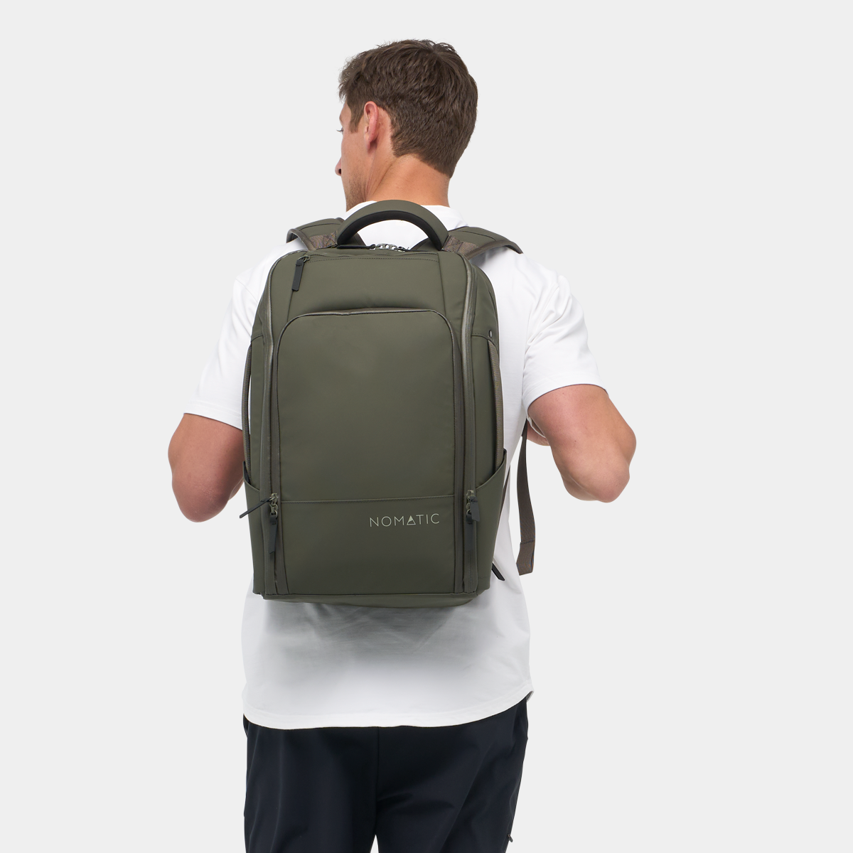 Nomatic Travel Pack in olive green worn by a man, showcasing its sleek, expandable design and weather-resistant fabric for travel organization.