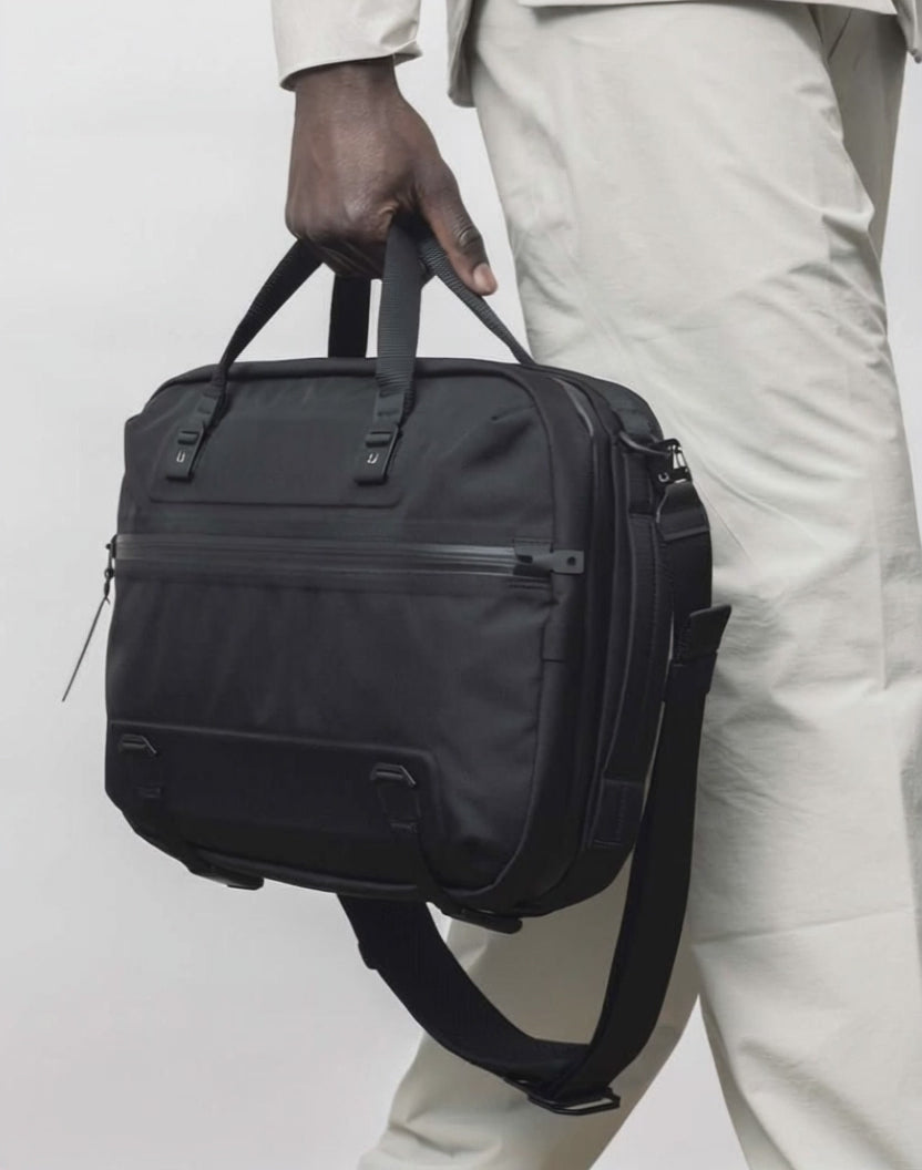 Black Ember FORGE SB 20L Minimalist Soft Brief in black carried by hand, showcasing its sleek EDC design and organized compartments for work essentials.